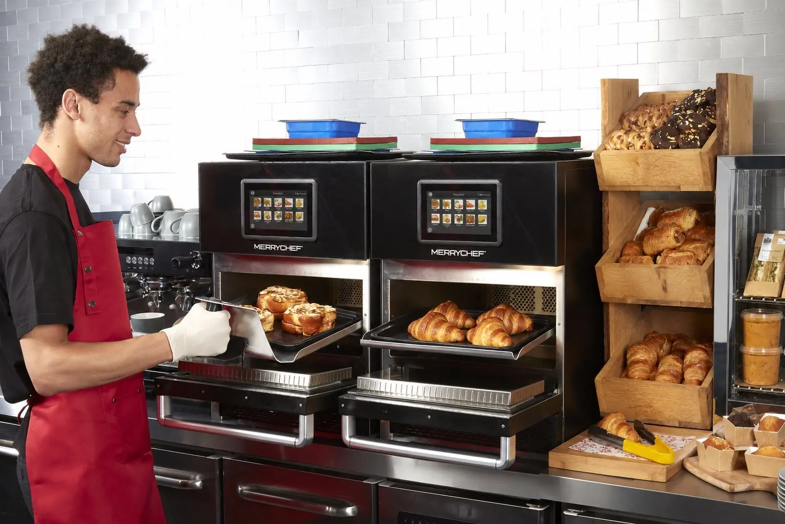 A c-store worker loading a Merco holding cabinet behind a bakery case